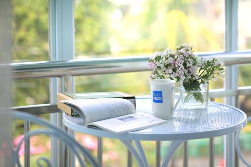 三亚克拉尔酒店•海岸精选的桌子,桌子上放着书,咖啡和鲜花