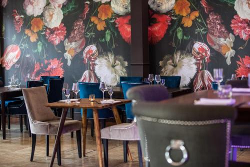 门兴格拉德巴赫圣乔治宫酒店的餐厅配有桌椅和花卉壁纸