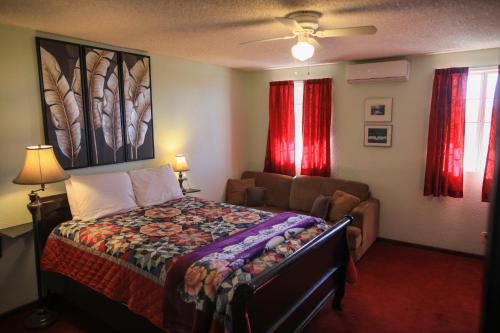 恩塞纳达港Playa Hermosa Inn at the beach的一间卧室配有床、沙发和红色窗帘