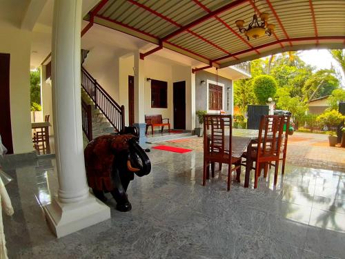 波隆纳鲁沃拉达旅客之家旅馆的一只奶牛站在门廊中间,配有桌椅