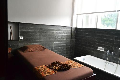 玛琅玛琅格兰德卡拉酒店的一间卧室配有一张床、一个浴缸和一个水槽