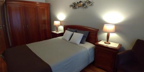 波尔图Apartamento Galerias的一间卧室配有一张带2个床头柜和2盏灯的床。