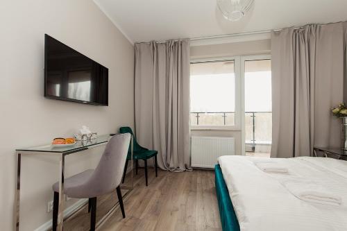 华沙Warsaw To Be - Silver Apartment的酒店客房配有书桌和床。