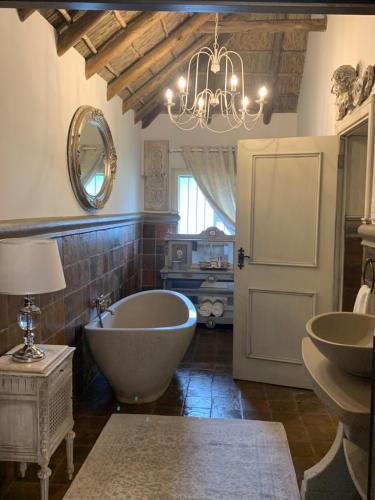 比勒陀利亚La-Perna Guesthouse and Venue的带浴缸、两个盥洗盆和吊灯的浴室。
