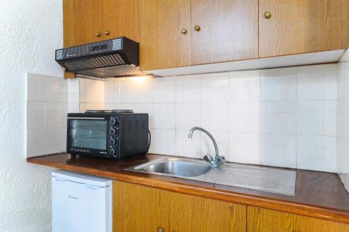 皮加迪卡Kritikos Apartments的厨房柜台配有微波炉和水槽