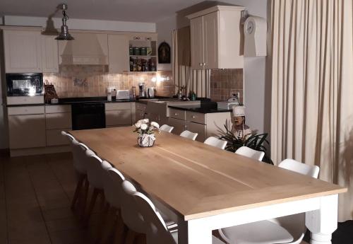 WaasmunsterVilla De Ruiter的厨房配有木桌和白色椅子