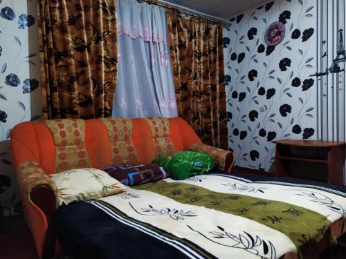 苏梅посуточная аренда Прокофьева 36的橙色沙发,坐在带窗帘的房间