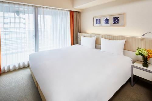 京都馨乐庭京都乌丸五条酒店的窗户客房内的一张大白色床