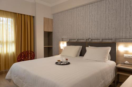 雅典泛酒店的一间酒店客房,配有一张床铺,上面放着一个食物托盘