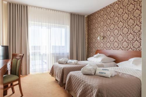 达布基BURSZTYN - BERNSTEIN SPA & Wellness的酒店客房设有两张床、一张书桌和一个窗户。