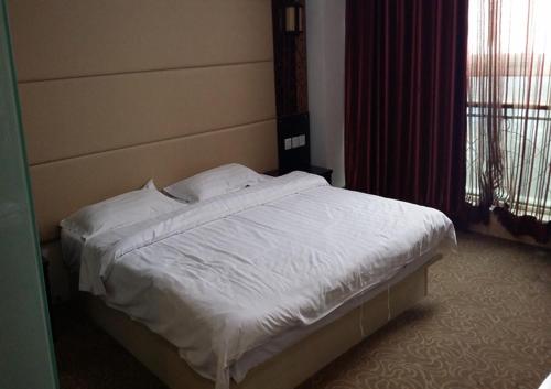 青岛尚客优酒店山东青岛黄岛崇明岛路店的卧室内的一张带白色床单和枕头的床