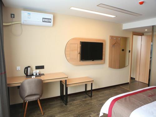 盐城尚客优酒店江苏盐城阜宁县金沙湖店的酒店客房设有一张桌子和一台墙上的电视。