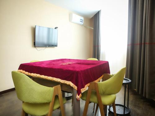 盐城尚客优酒店江苏盐城阜宁县金沙湖店的一张桌子、绿色椅子和红色桌布