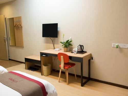 咸阳尚客优酒店陕西咸阳火车站店的一间卧室配有一张桌子、一台电脑和一张床