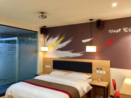 泉州尚客优酒店福建泉州丰泽区东海大街店的卧室配有一张床,墙上挂有绘画作品