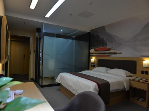 绵阳尚客优酒店四川绵阳御中路机场店的一间卧室设有一张大床和一个滑动玻璃门