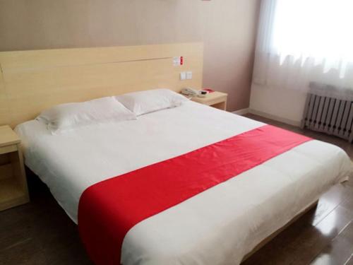 烟台尚客优酒店山东烟台高铁南站店的一间卧室配有一张大床,铺有红白毯子