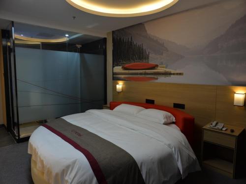 绵阳尚客优酒店四川绵阳御中路机场店的卧室配有一张大床,墙上挂有绘画作品