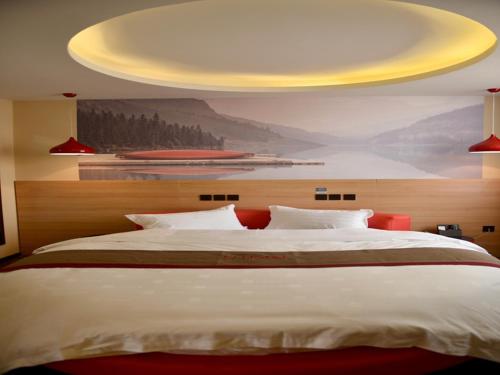 徐州尚客优酒店江苏徐州鼓楼区大黄山店的一间卧室设有一张黄色天花板的大床