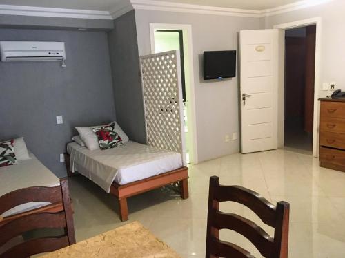 布希奥斯Pousada Marbella的一间卧室配有一张床、一把椅子和电视。