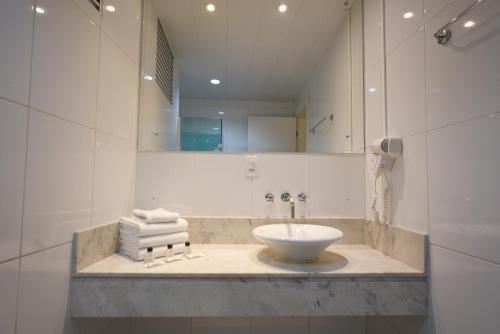库里提巴Hotel Dunamys Curitiba的浴室配有盥洗盆、镜子和毛巾