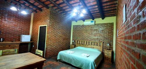 乌里韦拉雷亚La Maína Uribe Posada的一间卧室设有一张床和砖墙