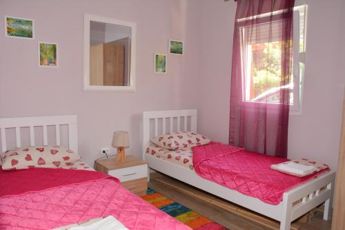 科托尔Vila Pelinovo的卧室内的两张床,配有粉红色的床单和窗户
