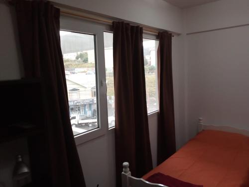 乌斯怀亚Seliuqanan的一间卧室设有2扇窗户和1张床铺