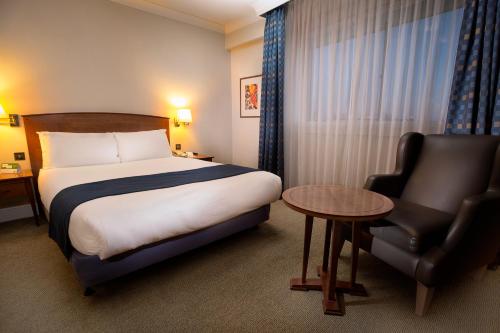 希灵登假日伦敦希斯罗艾丽尔酒店的配有一张床和一把椅子的酒店客房