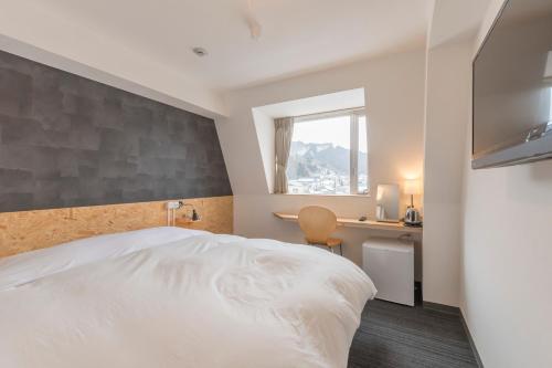 日光日光站酒店2的一间卧室配有一张床、一张书桌和一个窗户。