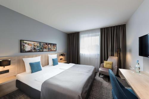 弗伦斯堡Ramada by Wyndham Flensburg的酒店客房设有一张大床和一张书桌。