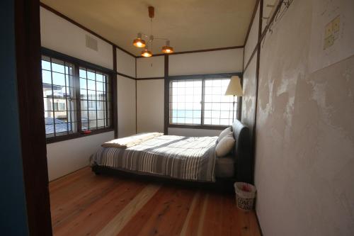 函馆kODATEL コダテル 函館シーサイド的一间卧室设有一张床和两个窗户。