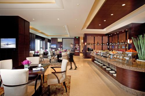 无锡无锡君来洲际酒店的餐厅设有酒吧,配有白色的椅子和桌子