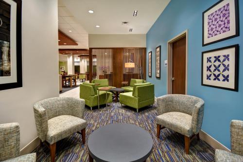 加尔维斯敦Holiday Inn Express & Suites - Galveston Beach, an IHG Hotel的一间设有绿色椅子和桌子的等候室
