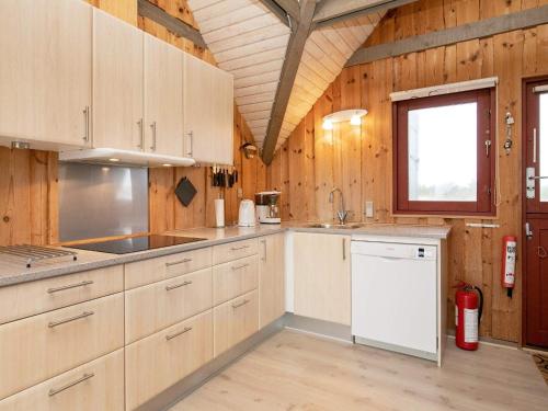 比耶勒高6 person holiday home in Hvide Sande的一个带木制橱柜和窗户的大厨房