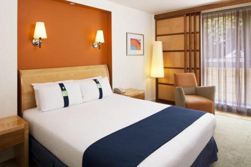 费勒姆假日法汉姆索伦特酒店的酒店客房带一张大床和一把椅子