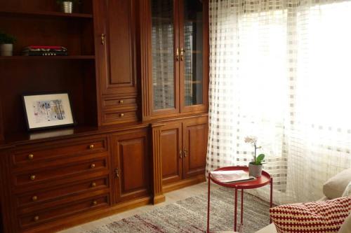 奥维多ÁTICO AUDITORIO disfrute sus 40 metros de terraza orientada al sur的一间卧室配有木制橱柜和一张红色桌子。