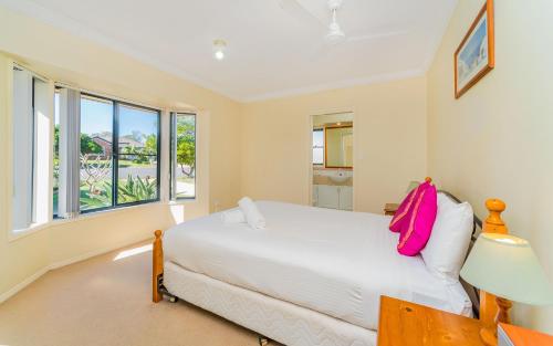 扬巴Oceania Cottage - LJHooker Yamba的卧室配有白色的床和窗户。