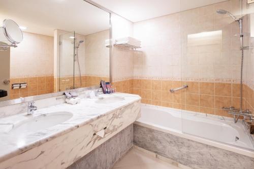沙迦Occidental Sharjah Grand的浴室配有2个盥洗盆和1个浴缸。