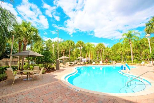 基西米Best Western Plus Orlando Lake Buena Vista South Inn & Suites的度假村的游泳池,配有桌椅和棕榈树