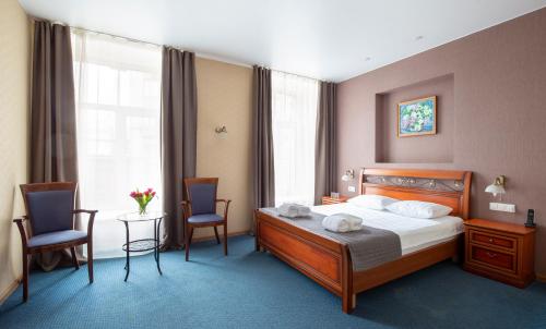 圣彼得堡Nevsky Grand Apartments的一间卧室配有一张床、两把椅子和一张桌子