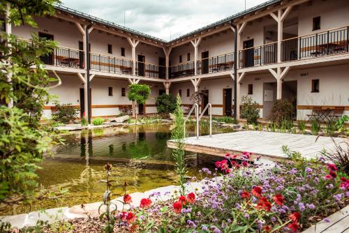 波切尼斯Penzión & Wellness MERIDIANA Bojnice rezort的一座带池塘和鲜花的建筑的庭院