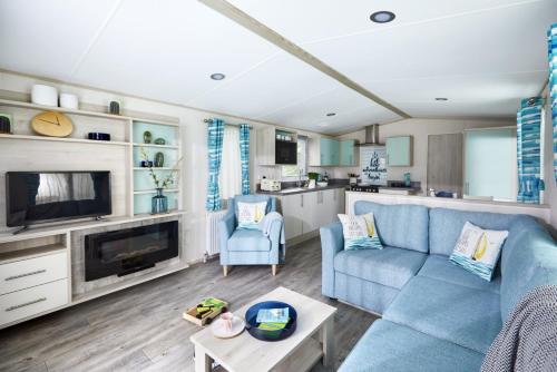雷讷瑟Siblu Camping de Oase的一间带蓝色沙发的客厅和一间厨房