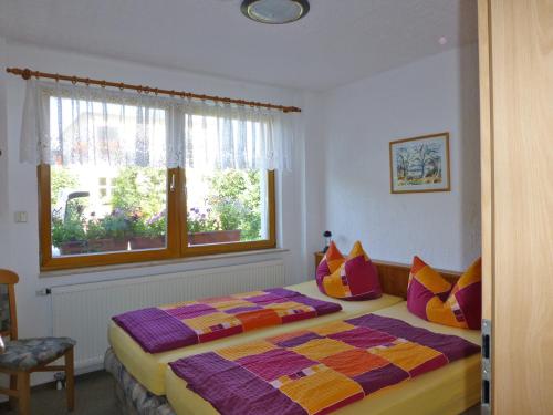格拉尔-米里茨Ostsee Ferienwohnungen und Ferienhäuschen的一间卧室配有一张带色彩缤纷枕头的床和窗户。