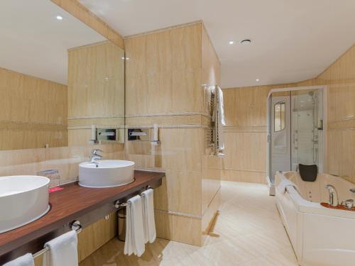 锡比乌锡比乌华美达酒店的一间带两个盥洗盆、浴缸和卫生间的浴室