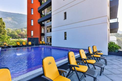 苏托莫雷Art-Hotel Del Medio的一座带黄色椅子的游泳池和一座建筑
