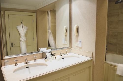韦尔文Melbourne Lodge的一间带两个盥洗盆和大镜子的浴室