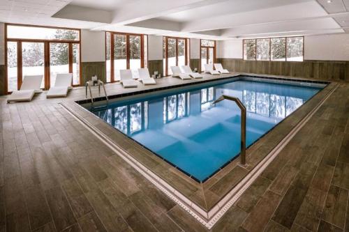 拉普德兹皮克布兰科酒店的大楼内带白色椅子的大型游泳池