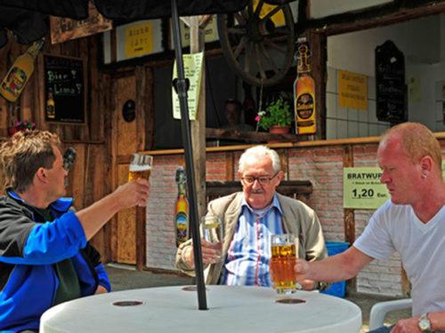 MainleusFränkischer Hof的坐在桌子上拿着杯啤酒的三个男人
