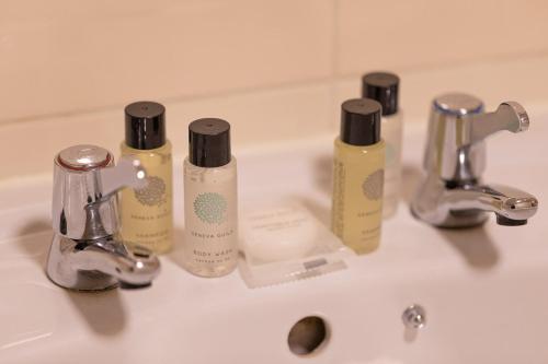 格洛斯特The New Inn by Roomsbooked的浴室水槽配有三瓶肥皂和两件水龙头